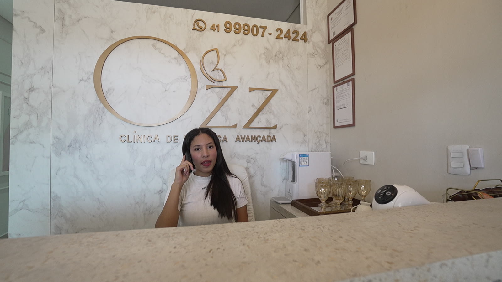Recepção da OZZ com a marca em relevo dourado sobre parede de mármore